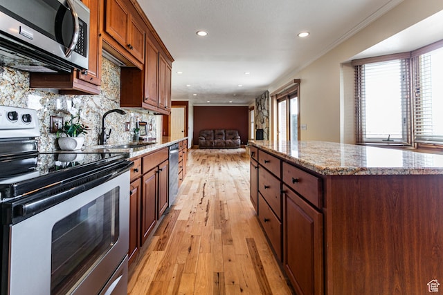 kitchen with light wood-style flooring, stainless steel appliances, a sink, ornamental molding, and backsplash