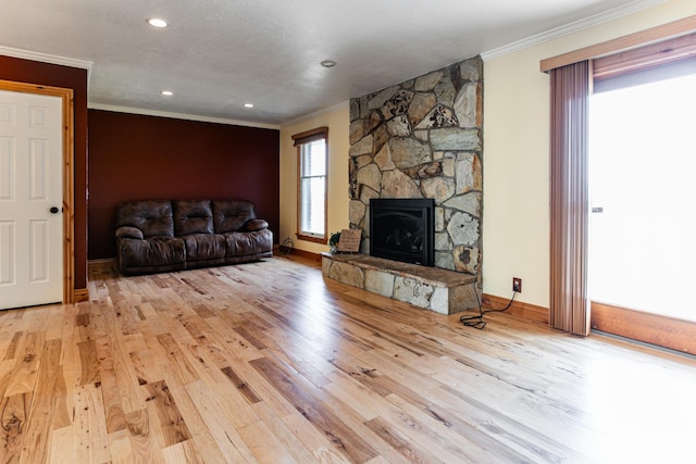 living area featuring ornamental molding, light wood-type flooring, a fireplace, and baseboards