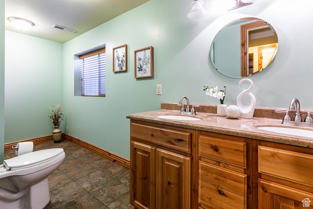 bathroom featuring visible vents, a sink, toilet, and double vanity