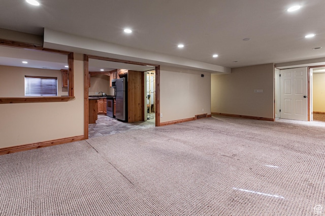 finished below grade area featuring recessed lighting, freestanding refrigerator, and light colored carpet