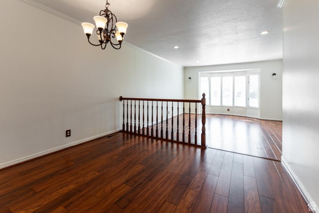spare room with baseboards, crown molding, a notable chandelier, and hardwood / wood-style floors