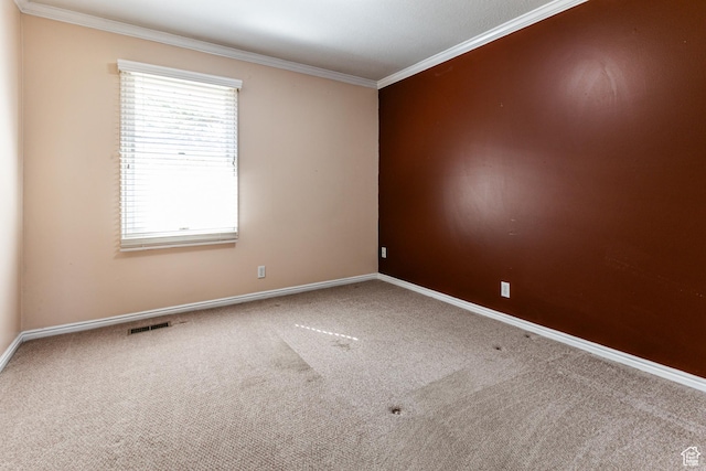 carpeted spare room with ornamental molding, visible vents, and baseboards