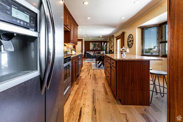 1963 E Rio Way E, Sandy, UT 84093 - kitchen with freestanding refrigerator, a kitchen breakfast bar, a kitchen island, light wood-type flooring, and recessed lighting