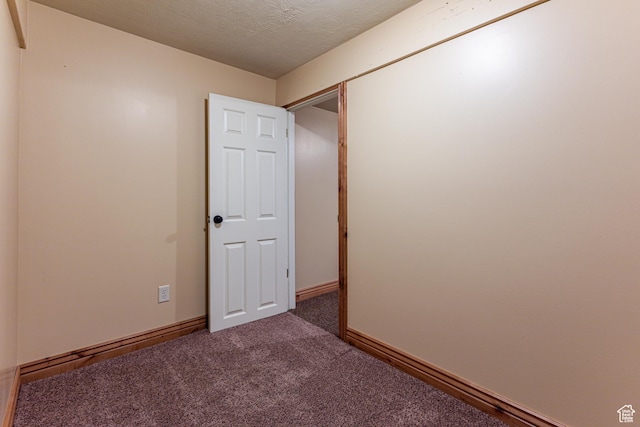 carpeted spare room with baseboards and a textured ceiling