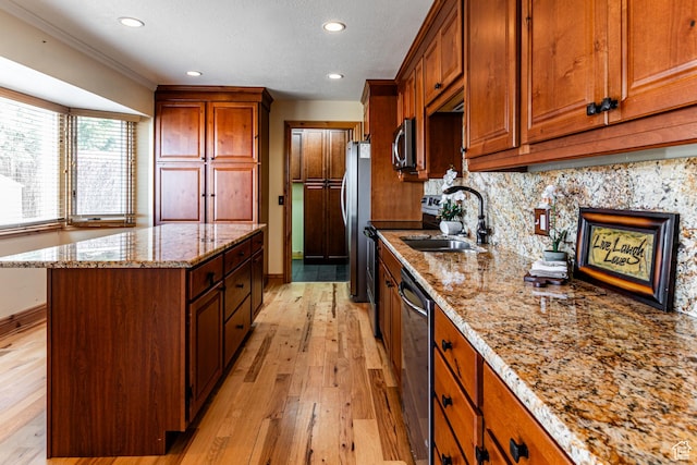 kitchen with light stone counters, stainless steel appliances, decorative backsplash, a kitchen island, and light wood-type flooring