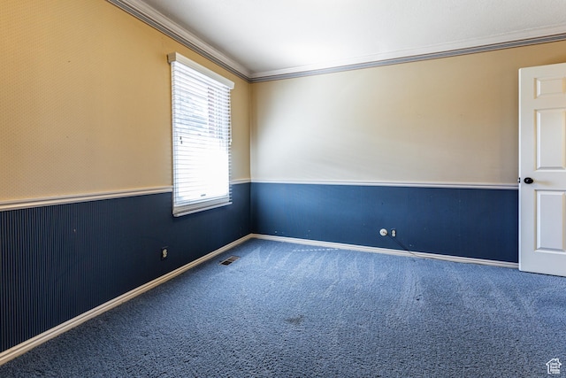 unfurnished room featuring a wainscoted wall, ornamental molding, carpet flooring, and visible vents