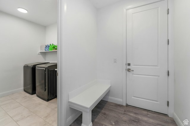 mudroom featuring light wood finished floors, baseboards, and separate washer and dryer