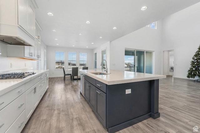kitchen with a sink, plenty of natural light, white cabinetry, light wood-style floors, and stainless steel gas stovetop