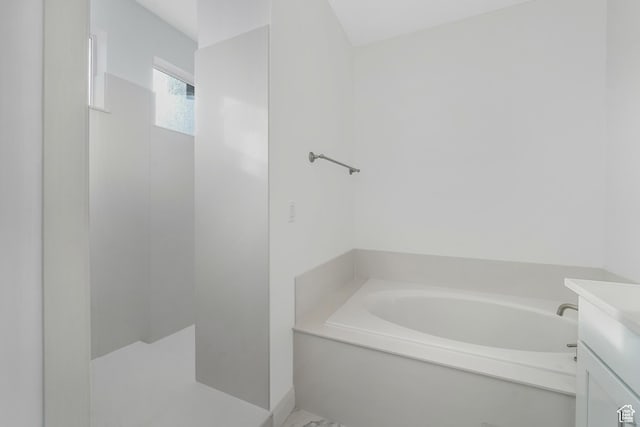bathroom featuring vanity, a bath, and walk in shower