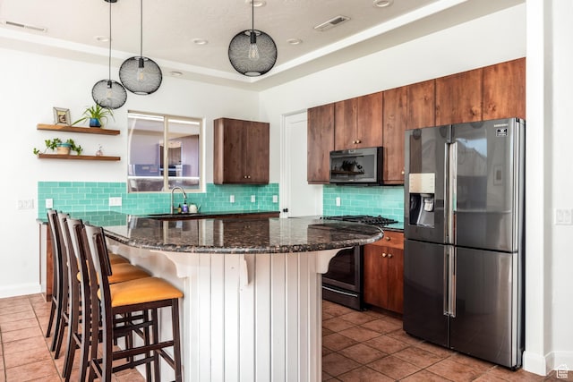 340 N Snow Canyon Dr Unit 4, Ivins, UT 84738 - kitchen with visible vents, decorative backsplash, a kitchen breakfast bar, dark stone countertops, and stainless steel appliances