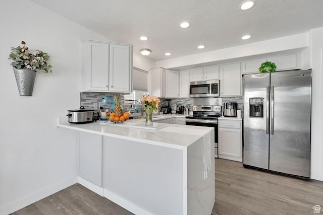 1087 N 1000 W, Clinton, UT 84015 - kitchen with stainless steel appliances, a peninsula, backsplash, and light wood-style flooring