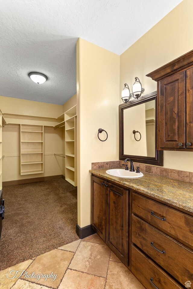 2275 E Rustic Dr, St George, UT 84790 - bathroom with a textured ceiling, a spacious closet, vanity, and baseboards