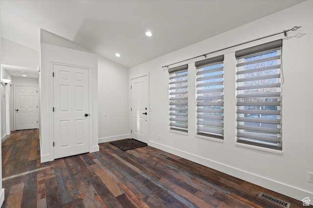 foyer entrance featuring baseboards, wood-type flooring, lofted ceiling, visible vents, and recessed lighting
