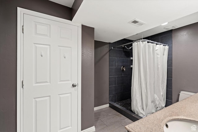 bathroom featuring baseboards, vanity, visible vents, and tiled shower