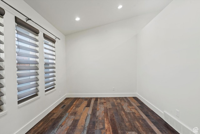 empty room with dark wood-type flooring, visible vents, baseboards, and recessed lighting