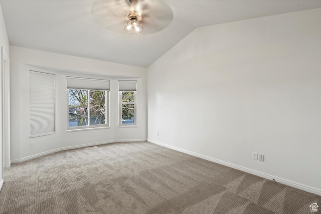 carpeted empty room with lofted ceiling, baseboards, ceiling fan, and visible vents