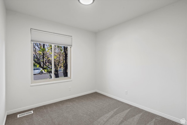 spare room featuring baseboards, visible vents, and carpet