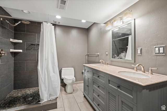 full bathroom with toilet, tiled shower, and a sink