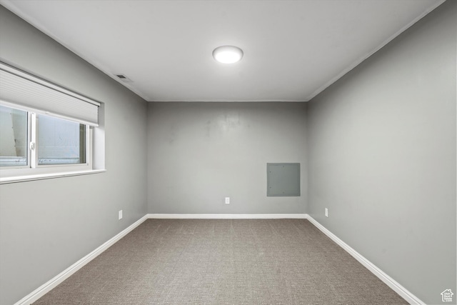 carpeted spare room with visible vents, electric panel, and baseboards