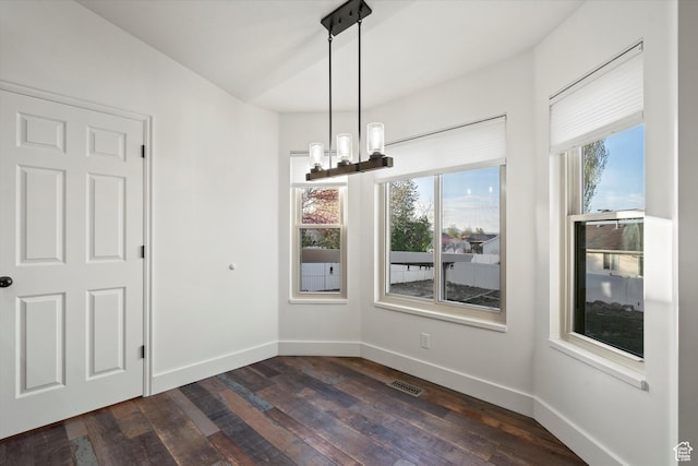 unfurnished dining area featuring dark wood finished floors, visible vents, baseboards, and a notable chandelier