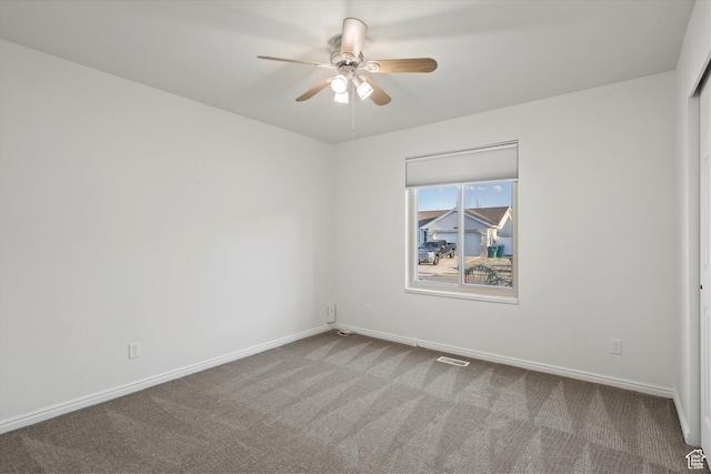 carpeted empty room featuring visible vents, baseboards, and ceiling fan