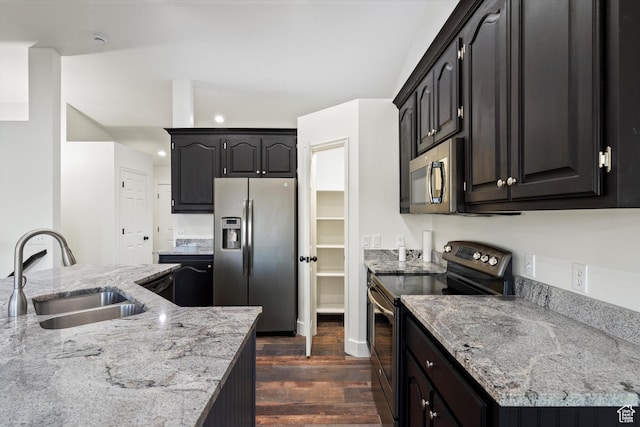 kitchen with light stone countertops, appliances with stainless steel finishes, dark wood-style floors, and a sink