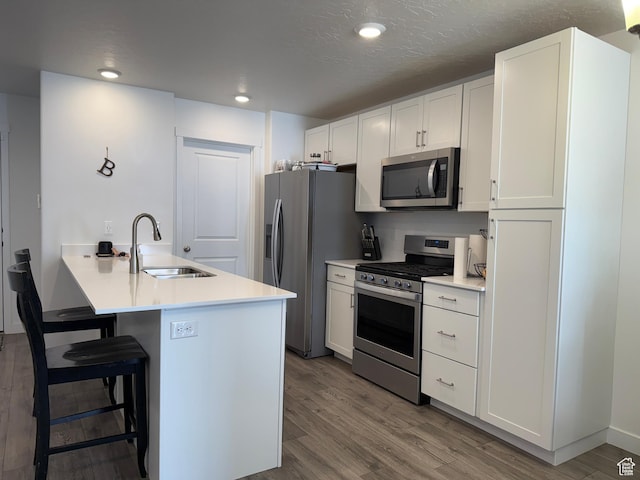 2810 N Fighting Falcon St, Layton, UT 84040 - kitchen featuring a breakfast bar area, wood finished floors, a sink, and stainless steel appliances