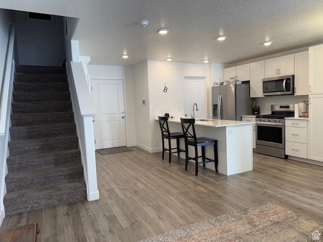2810 N Fighting Falcon St, Layton, UT 84040 - kitchen with baseboards, a sink, a breakfast bar, stainless steel appliances, and light wood-style flooring
