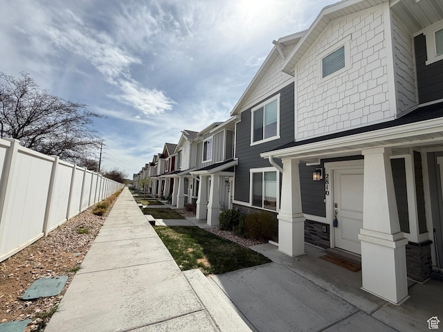 view of property exterior with a porch, a residential view, and fence
