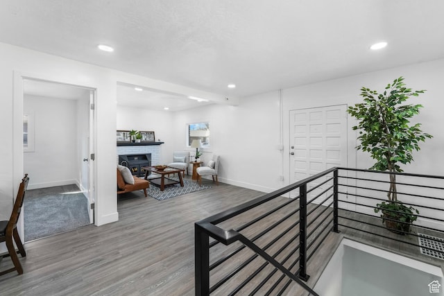 hallway featuring recessed lighting, baseboards, wood finished floors, and an upstairs landing