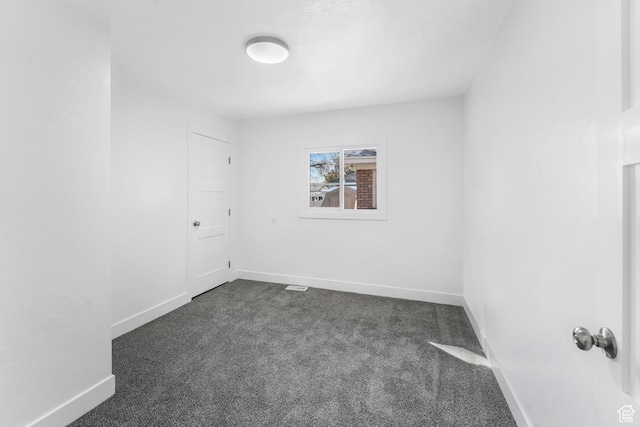spare room with dark colored carpet and baseboards