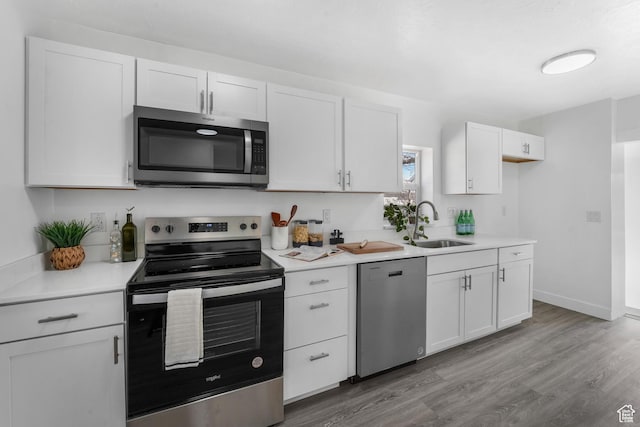 kitchen featuring appliances with stainless steel finishes, light countertops, white cabinetry, and wood finished floors