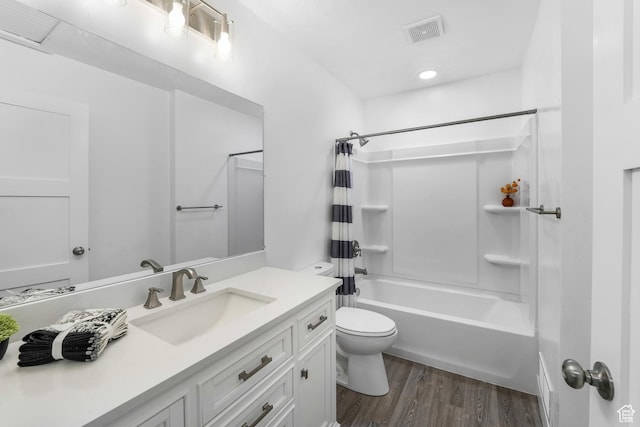 full bathroom with visible vents, toilet, shower / bath combo with shower curtain, vanity, and wood finished floors