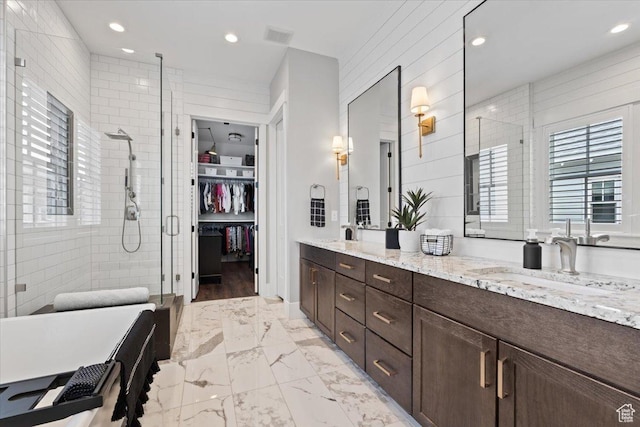 bathroom featuring marble finish floor, double vanity, a sink, and a shower stall