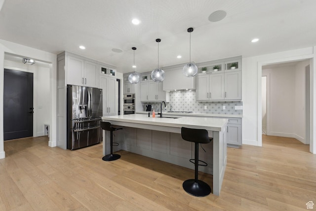kitchen featuring light wood-type flooring, appliances with stainless steel finishes, light countertops, and a kitchen breakfast bar