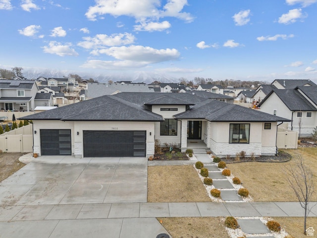 view of front of home with concrete driveway, an attached garage, a gate, fence, and a residential view