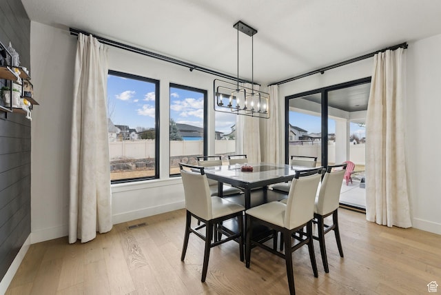 dining space with light wood-style floors, visible vents, and baseboards