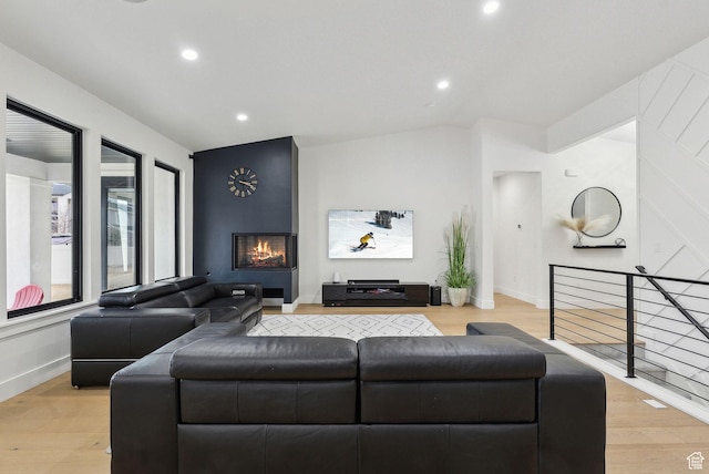 living area featuring lofted ceiling, light wood-type flooring, a fireplace, and recessed lighting