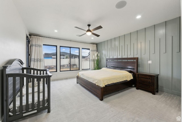 carpeted bedroom with a ceiling fan, recessed lighting, and a decorative wall
