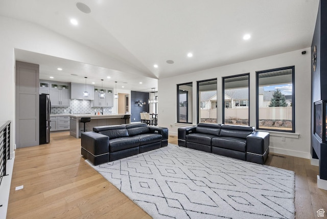 living area with light wood-type flooring, lofted ceiling, and recessed lighting