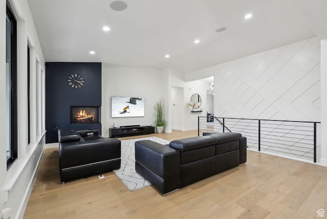 living room featuring light wood-style floors, an accent wall, a fireplace, and recessed lighting