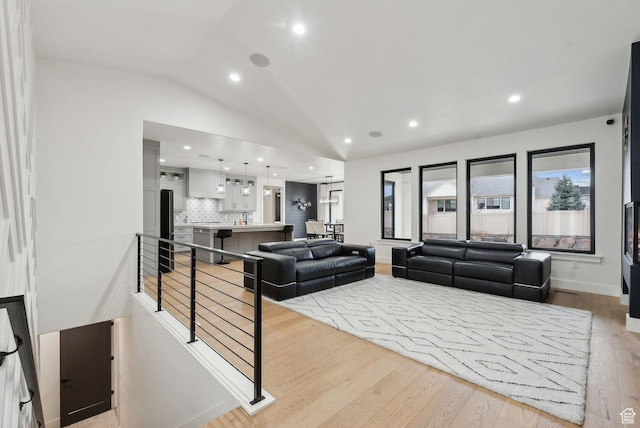living area with lofted ceiling, light wood finished floors, baseboards, and recessed lighting