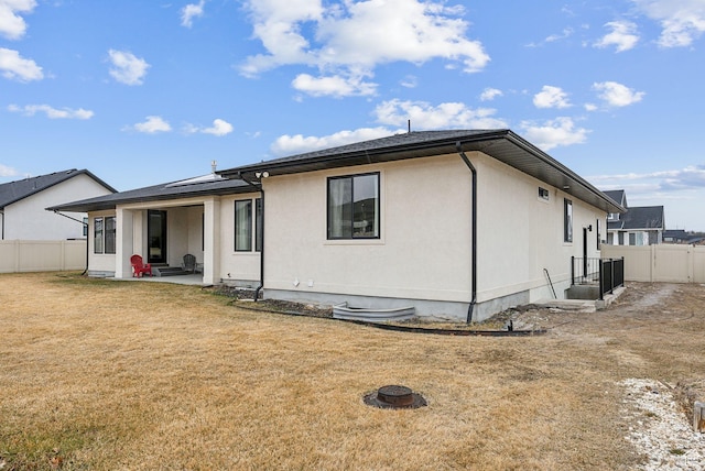 rear view of house with a patio, an outdoor fire pit, a fenced backyard, solar panels, and a lawn