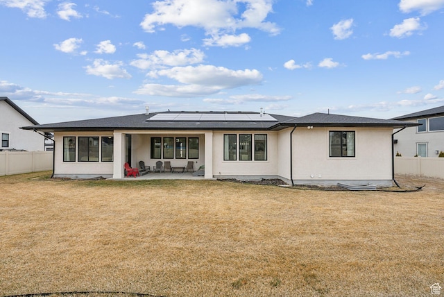 back of house featuring solar panels, a yard, a patio area, and fence
