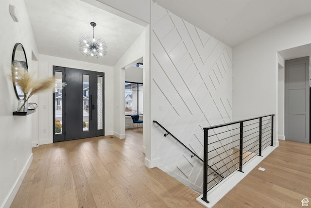 foyer entrance featuring a chandelier, lofted ceiling, baseboards, and wood finished floors