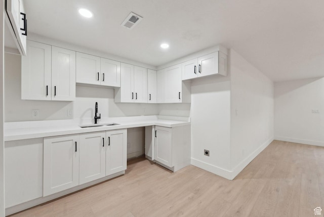 kitchen with light wood-style floors, visible vents, white cabinets, and a sink