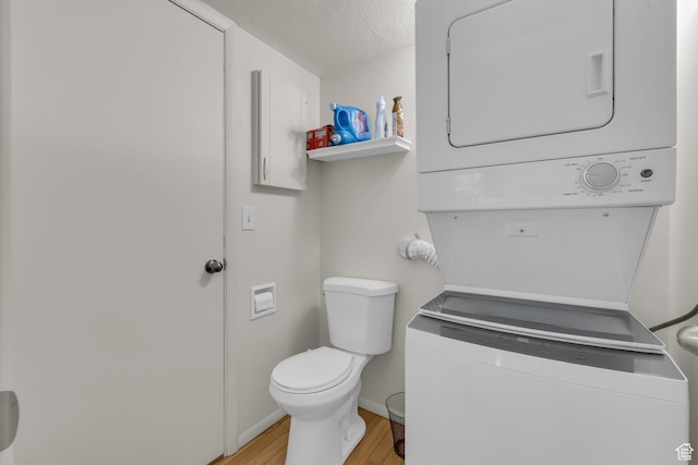 1384 Millcreek Dr Unit 6, Ogden, UT 84404 - bathroom with toilet, wood finished floors, stacked washing maching and dryer, a textured ceiling, and baseboards