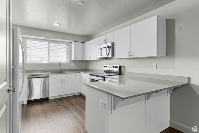 128 N Lone Rock Dr Unit 202, Hurricane, UT 84737 - kitchen with appliances with stainless steel finishes, dark wood-style flooring, a peninsula, white cabinetry, and a sink