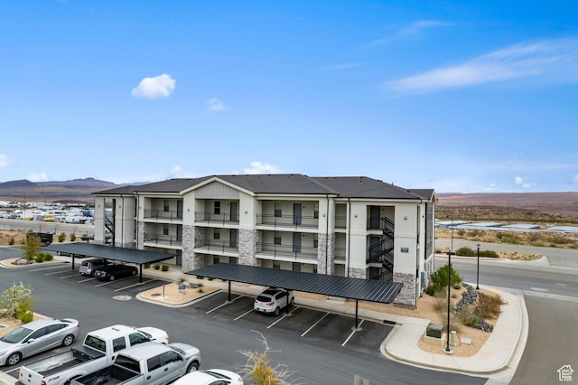 view of building exterior with covered and uncovered parking and a mountain view