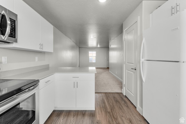 128 N Lone Rock Dr Unit 202, Hurricane, UT 84737 - kitchen with stainless steel appliances, a peninsula, white cabinetry, light countertops, and dark wood-style floors